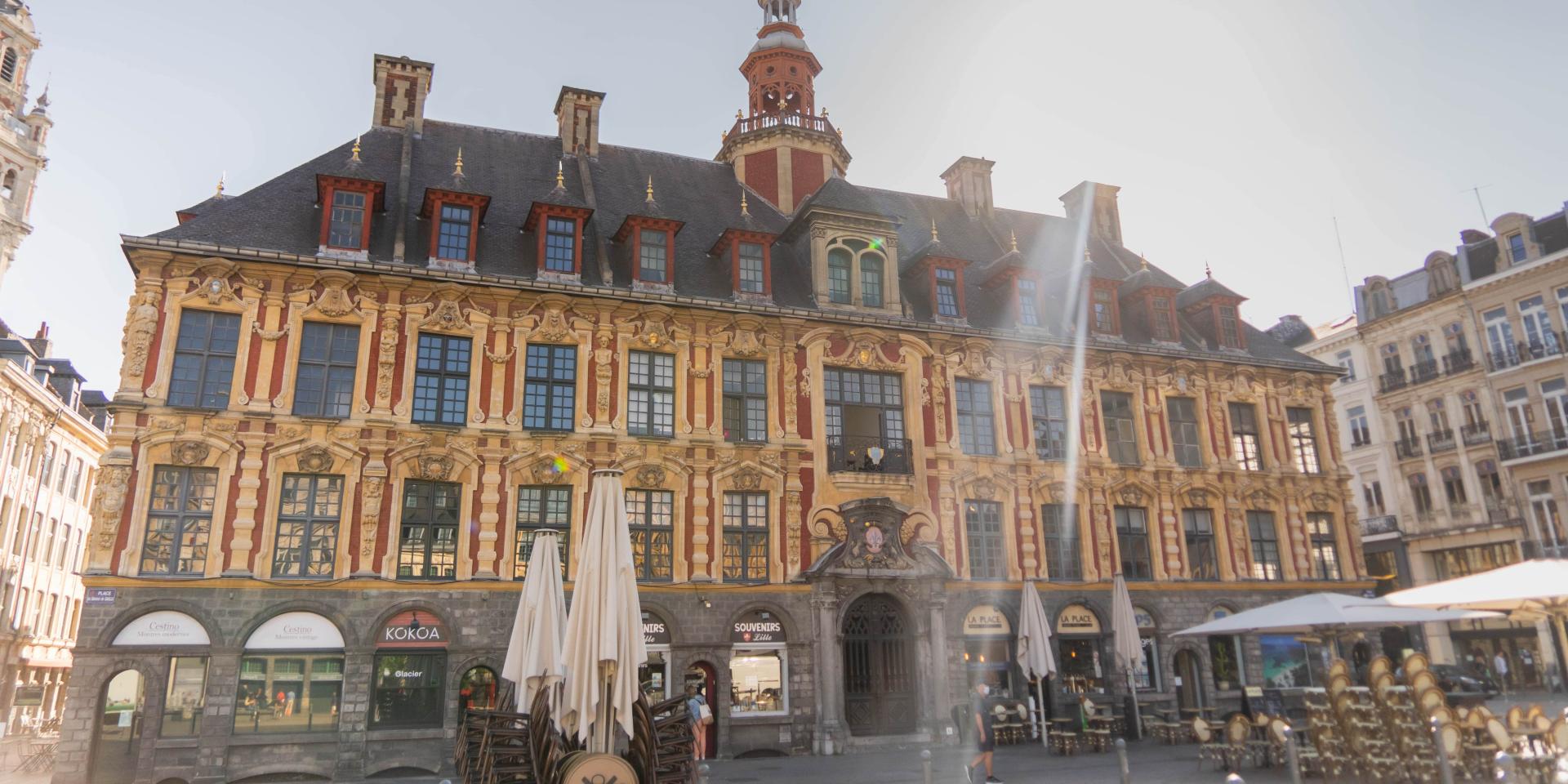 Façade de la Vieille Bourse à Lille, vue depuis la place, avec ses briques rouges, ses décors dorés et son campanile. Photographie Laurent Javoy – Hello Lille, publiée par l’Office de Tourisme de Lille.