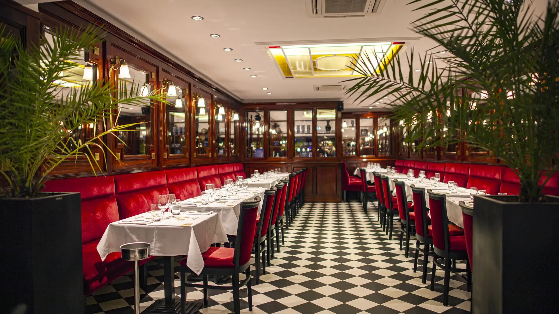 Vue d'ensemble de la salle du Bouillon Rihour : banquettes rouges, miroirs, boiseries et sol en damier. Crédit Marie ANTROPE, fiche officielle du restaurant sur Lille Tourisme.